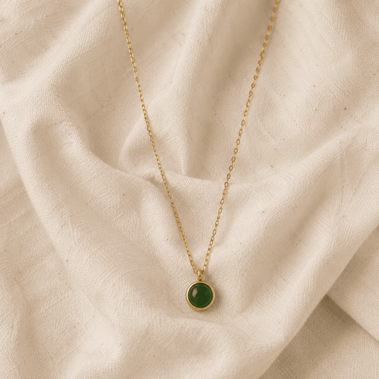 A handwritten thank-you card resting on cream silk beside a gold pendant